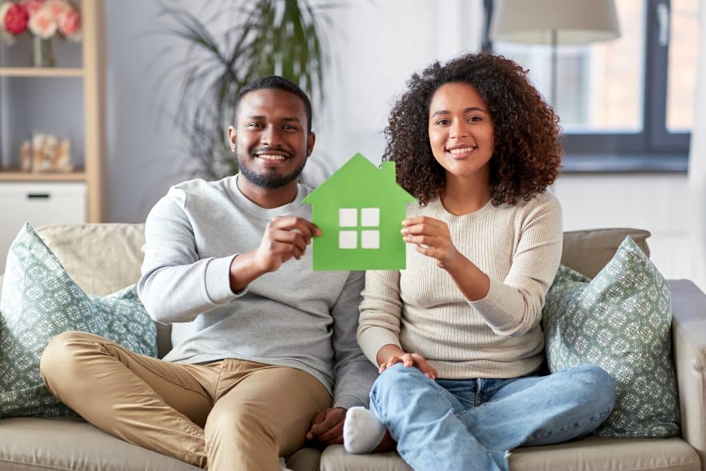a young couple holding up a visual representation of an eco-friendly home.