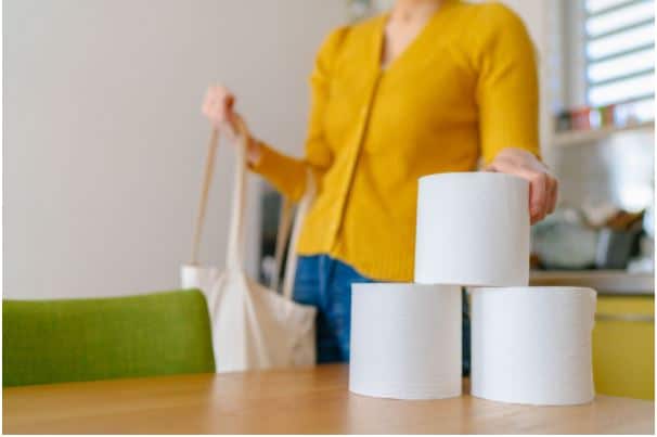 Woman places toilet rolls on table after shopping