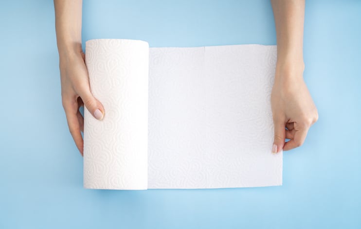 a woman tears a sheet of paper off a kitchen roll.